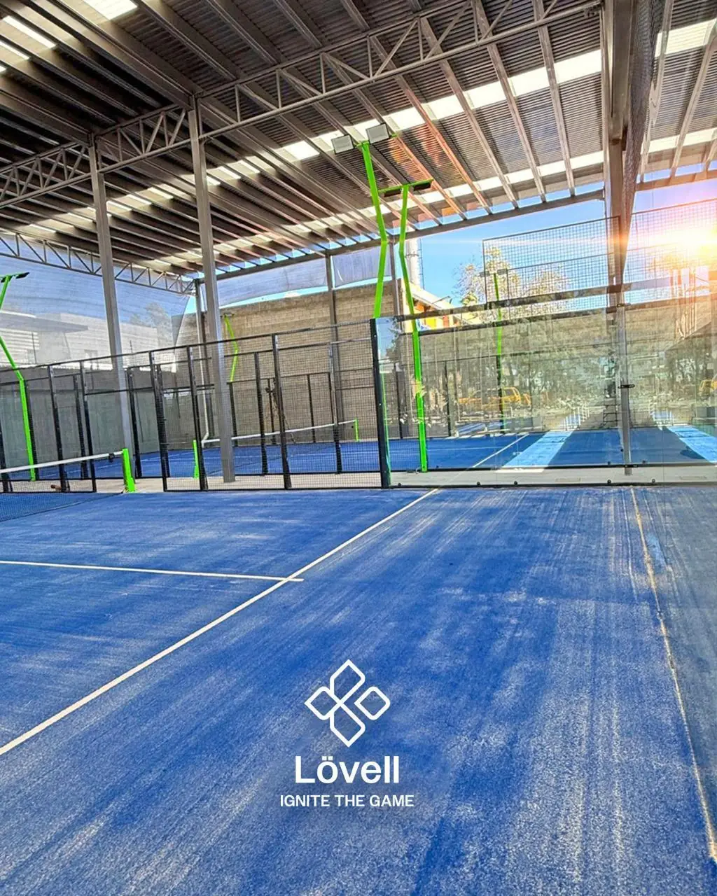 Canchas de pádel azules techadas bajo una estructura metálica, con postes de luz en V verdes, en Guanajuato
