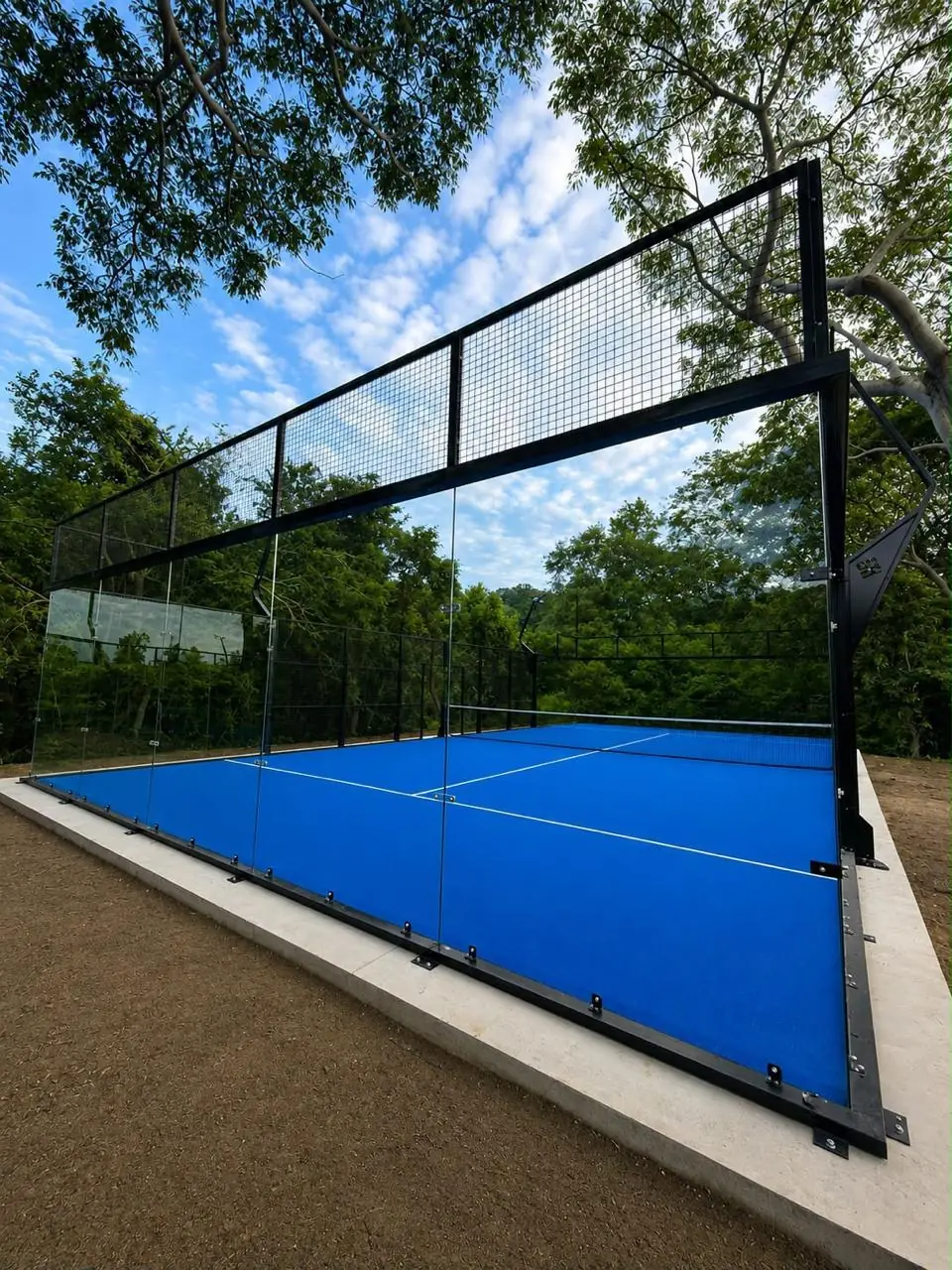 Cristal templado y malla superior de una cancha de pádel panorámica entre árboles en Guerrero