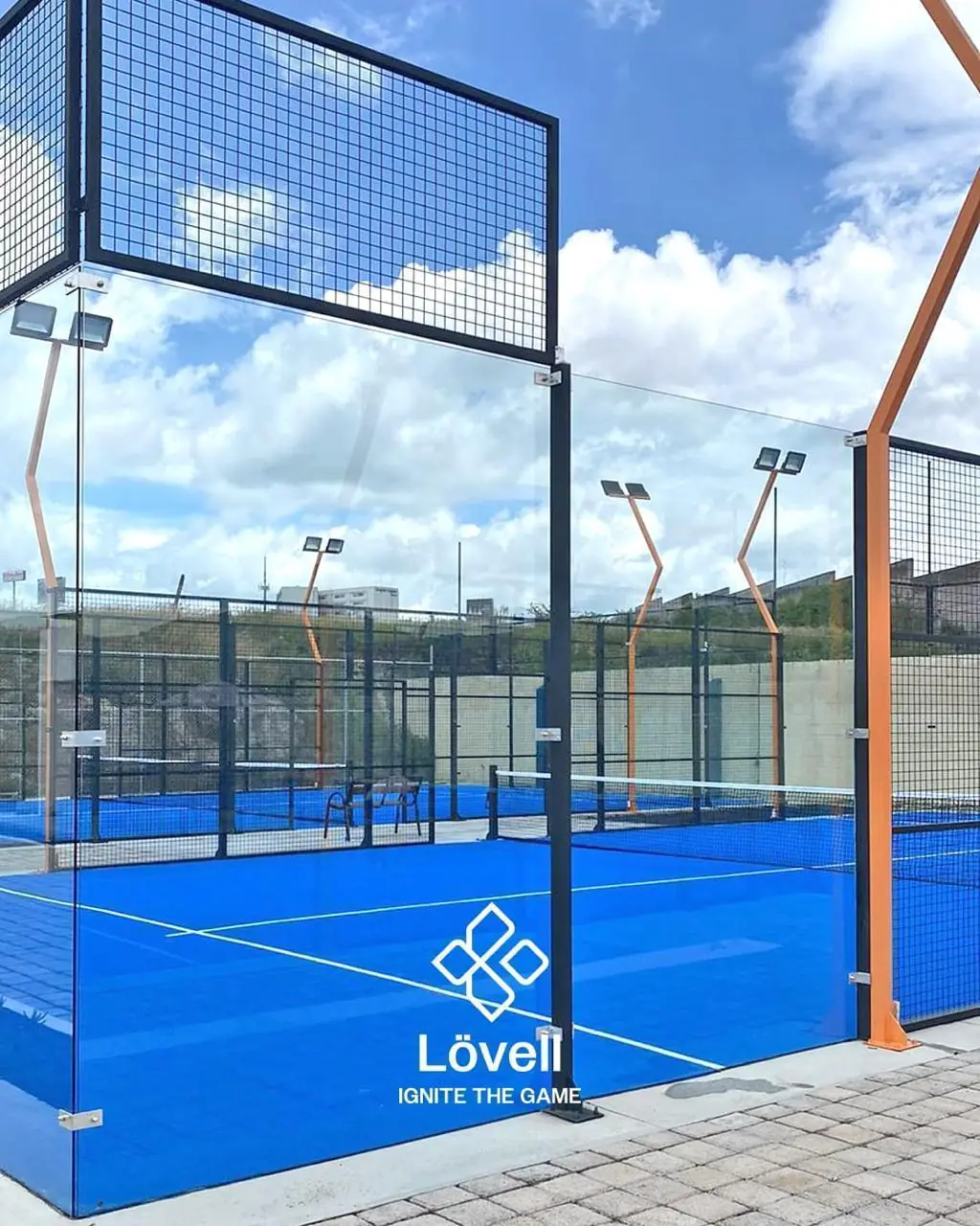 Canchas de pádel panorámicas azules con postes de luz en V naranjas en un club de Michoacán